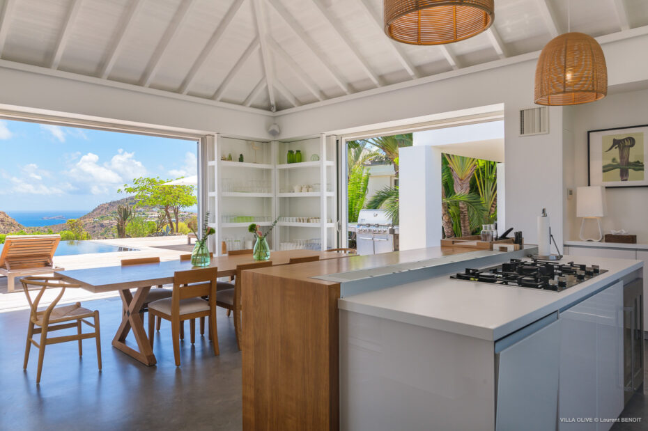Modern villa kitchen opening to terrace and infinity pool